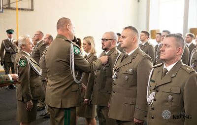 hala sportowa. generał przypina medal odznaczonym funkcjonariuszom.