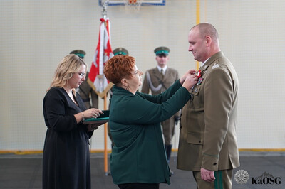 hala sportowa. przewodnicząca związku zawodowego pracowników mswiap przypina medal generałowi
