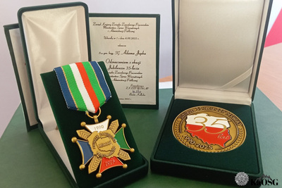 odznaka i pamiątkowy medal położone na zielonej desce. otrzymał je generał podczas uroczystości