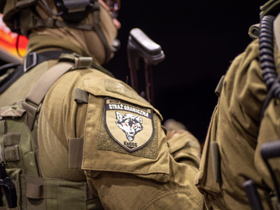 funkcjonariusz grupy szturmowej w pełnym umundurowaniu, zbliżenie na ramię z emblematem i napisem wzd kaosg