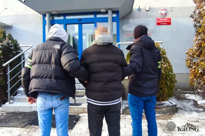 Na zdjęciu przed budynkiem stoją trzy osoby. Jest zimno, ubrani są w ciepłe ciuchy.