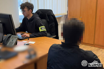 zatrzymany cudzoziemiec siedzi przy funkcjonariuszu sg, który jest ubrany w strój cywilny z opaską odblaskową na ręku z napisem straż graniczna