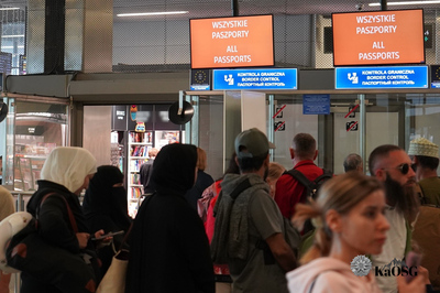 Na zdjęciu widać odprawę paszportową na lotnisku. U góry widać napisy informujące, że do kontroli można podchodzić z każdym paszportem. Widać tłum ludzi czekających na odprawę.