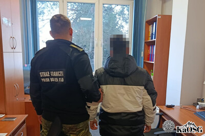 Zatrzymany obywatel indii stoi w asyście funkcjonariusza sg w pomieszczeniach placówki sg w krakowie