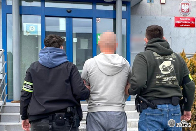 Na zdjęciu widać trzy osoby, które stoją przed budynkiem