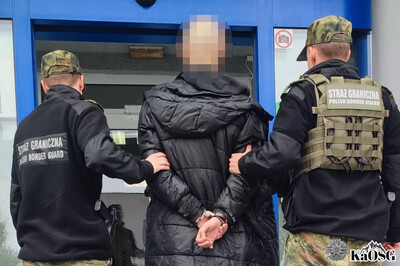 dwóch funkcjonariuszy prowadzi zatrzymanego obywatela tadżykistanu do siedziby placówki sg w krakowie