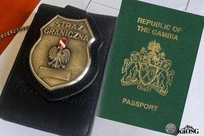 Obok paszportu obywatela Gambii leży odznaka straży granicznej