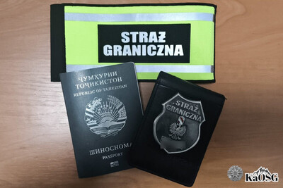 Paszport obywatela tadżykistanu i odznaka funkcjonariusza straży granicznej leżą na biurku