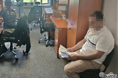 pomieszczenia biurowe placówki sg. zatrzymany cudzoziemiec siedzi na krześle, przy biurku siedzi funkcjonariuszka sg
