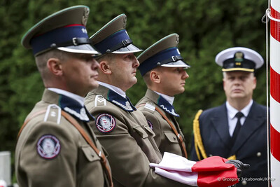 funkcjonariusze straży granicznej w poczcie flagowym. Jeden z funkcjonariuszy trzyma flagę Polski.