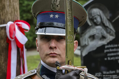 Funkcjonariusz Straży Granicznej w pozycji na baczność przed sobą trzyma szablę.