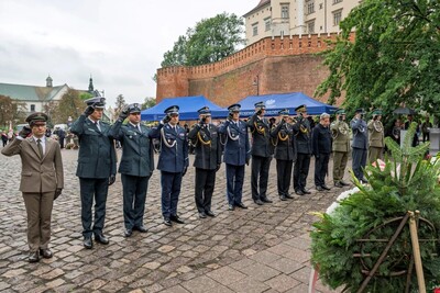 Przedstawiciele służb mundurowych oddający honor przed pomnikiem.