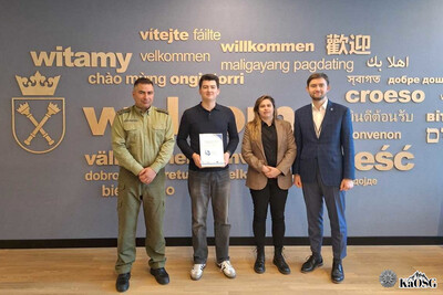 prelegenci stoją na tle ściany z logotypem uniwersytetu jagiellońskiego z napisem witamy w różnych językach